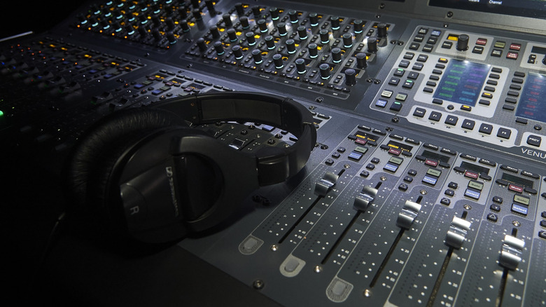 A pair of high-end headphones resting on a studio mixing console