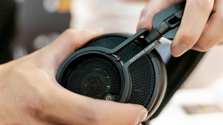 A closeup of someone manipulating a pair of high-end headphones