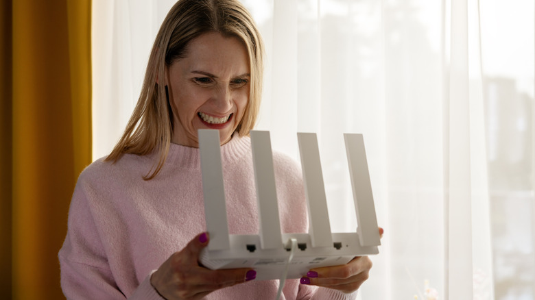 women holding a white router, frustrated due to slow internet speeds