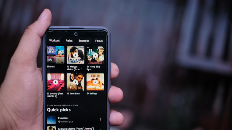 Hand holding smartphone with YouTube Music playing