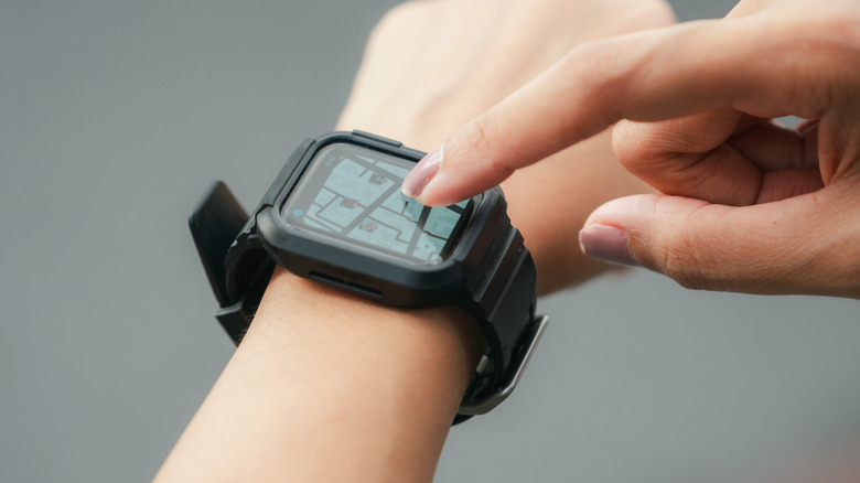 A finger on a smartwatch on a wrist showing a map.