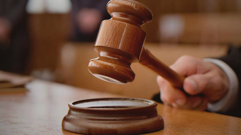A hand swinging a gavel towards a sound block