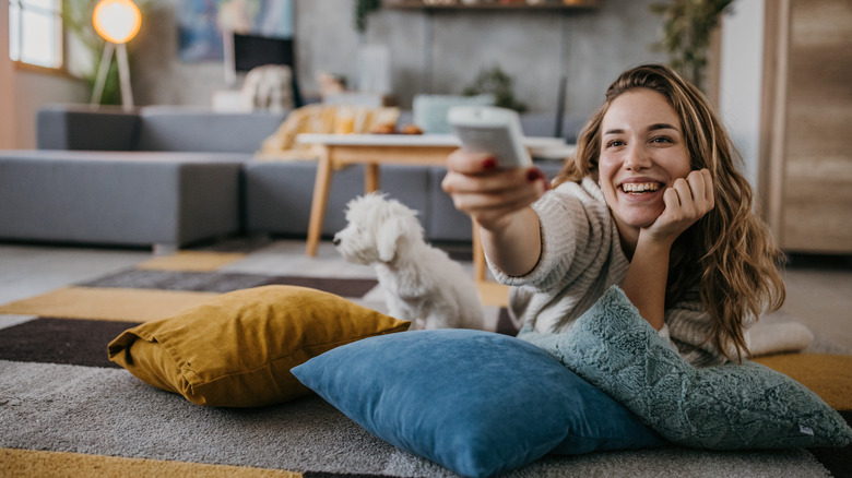 a woman lying on the floor with her dog and watching TV happily