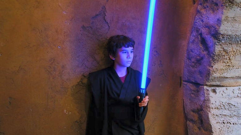 Boy looking at Adafruit 3d printed lightsaber with blue blade