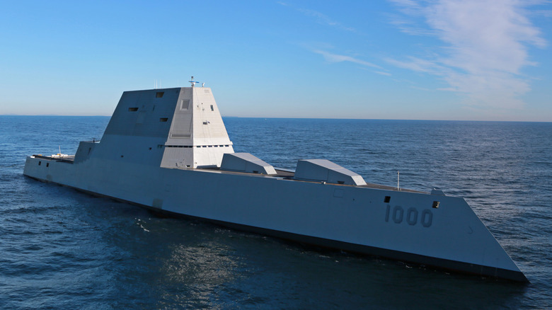 A side view shows the angular hull of the DDG-1000 Zumwalt as it sails through open water.