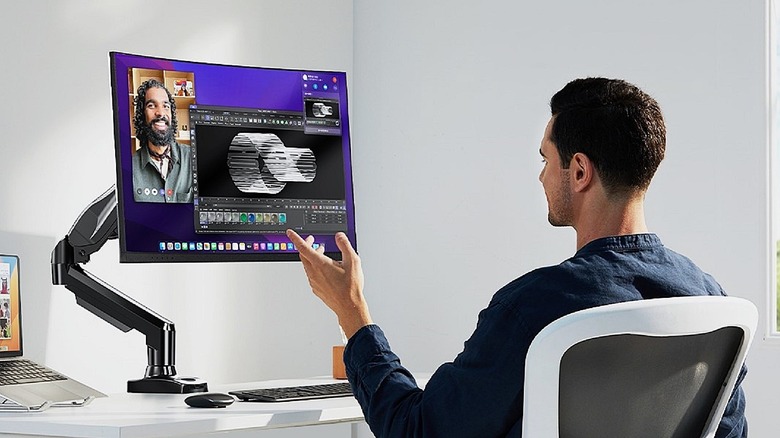 Huanuo monitor mounting arm holding display while man video chats.