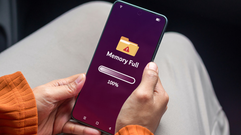 A person holding a phone displaying a memory full warning on the screen