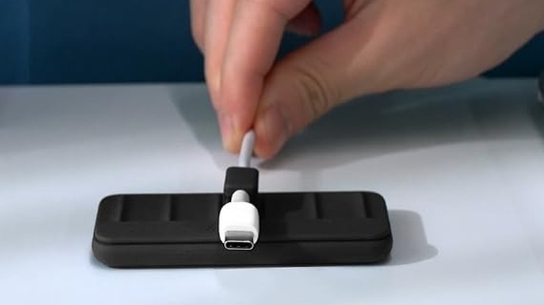 A person holding a USB-C cable to the Anker Multipurpose Cord Keeper.