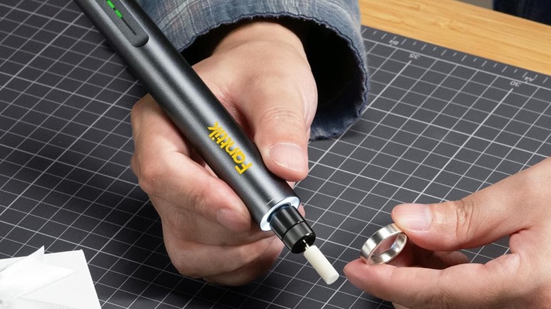 An individual holding a Fanttik F2 Master Rotary Tool Kit in their right hand