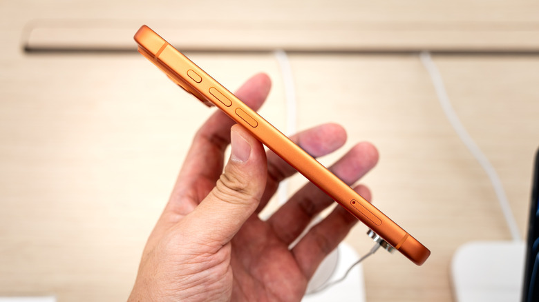 A man holding an orange iPhone Air with its side to the camera, showing how thin it is