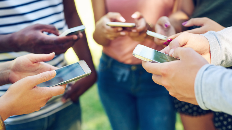 Close-up of young people's hands using phones together