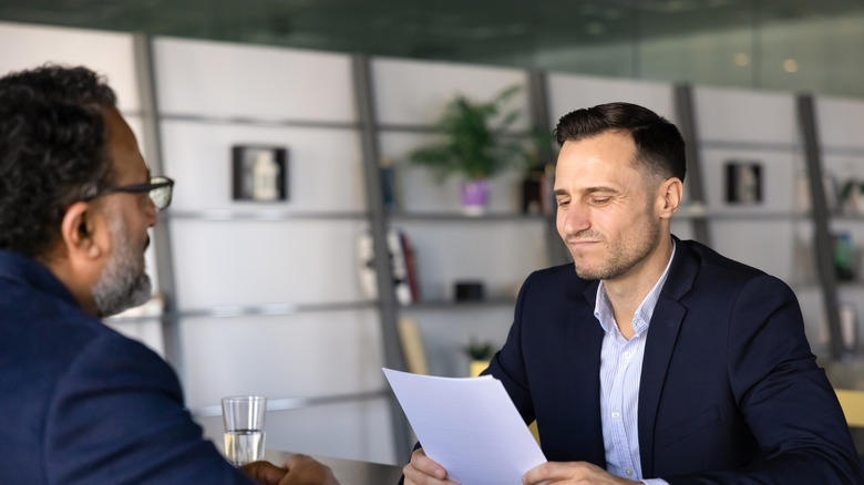Man looking down at papers with a skeptical look on his face