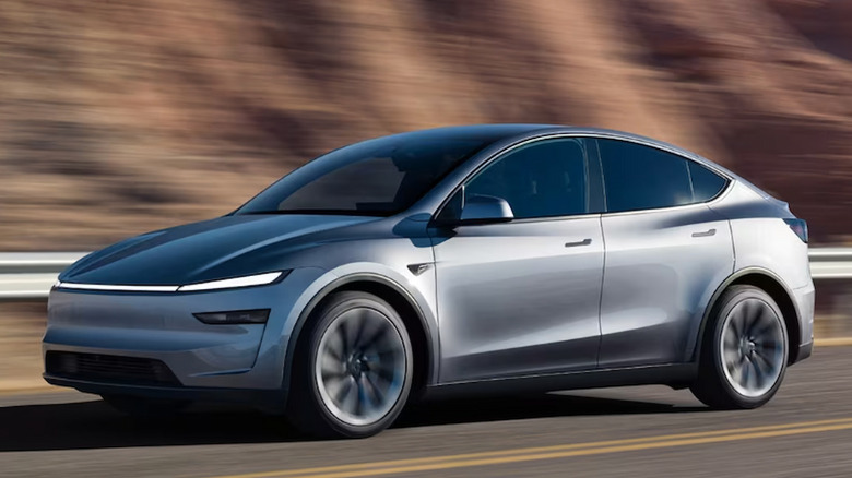 A gray Tesla Model Y Juniper driving along a road