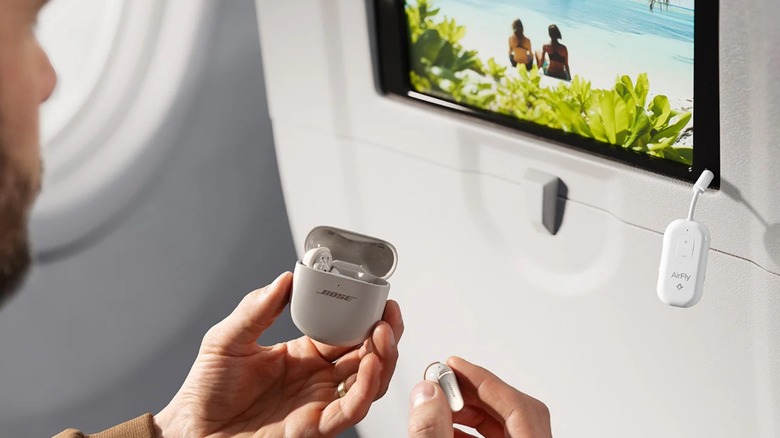 A man pairing their wireless earbuds with Twelve South's AirFly Pro 2 on a plane