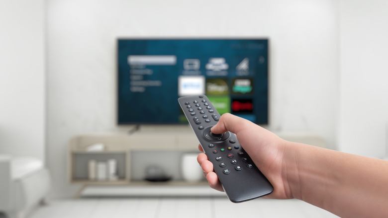 Hand holding remote and pointing it at TV screen