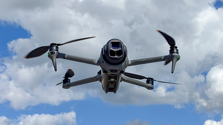 DJI Mavic 4 Pro quadcopter drone flying in the sky with clouds in the background