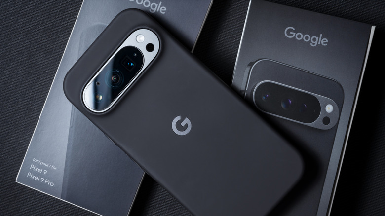 A Google Pixel 9 in a black case sitting atop its box