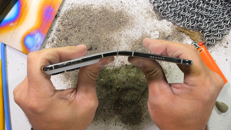 A top-view image showing Zack Nelson of JerryRigEverything bending the iPhone Duo with his hands