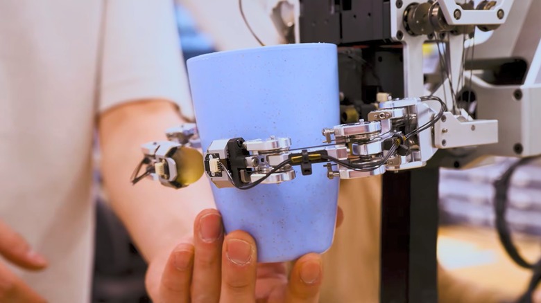 Person holding a blue cup as a robotic hand grips it