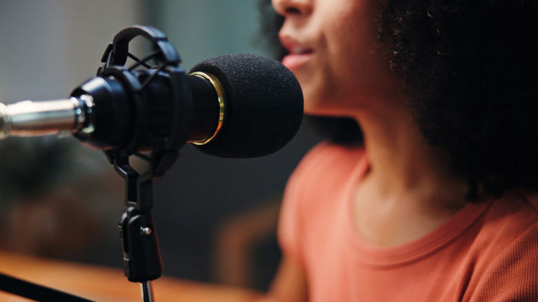 A woman talks into a micropohone that has a foam cover on it