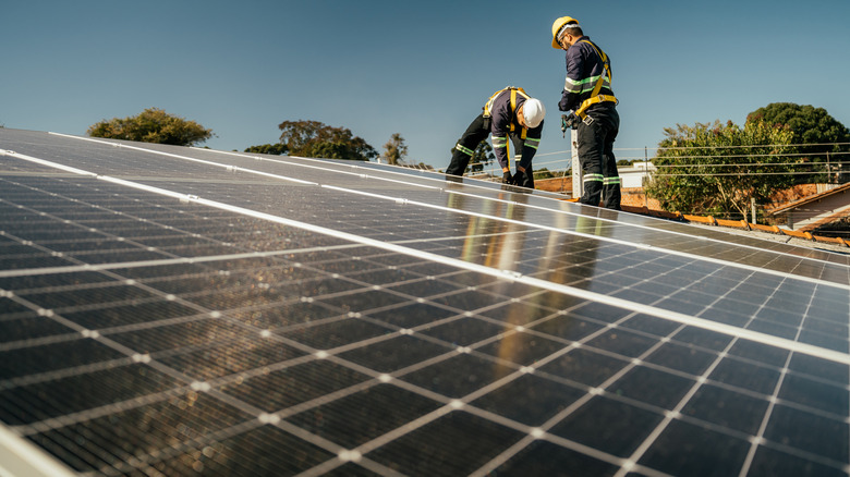 Two construction workers working on a solar panel on a house roof