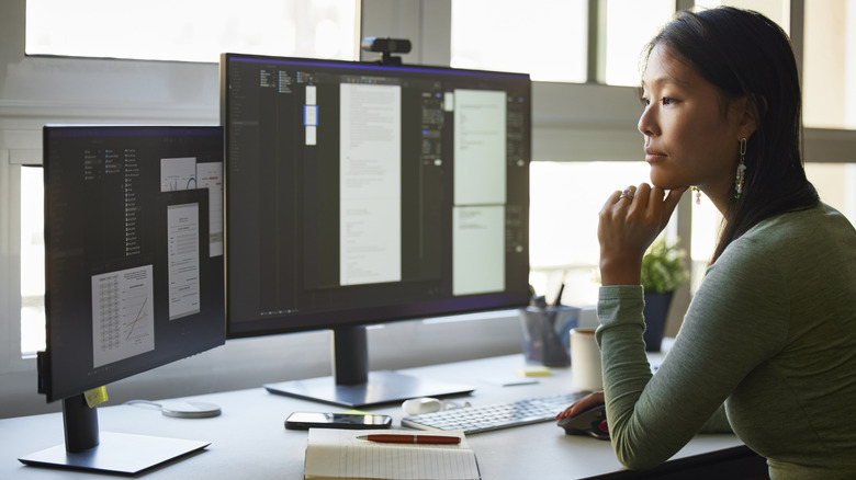 A woman sitting in front of two monitors.