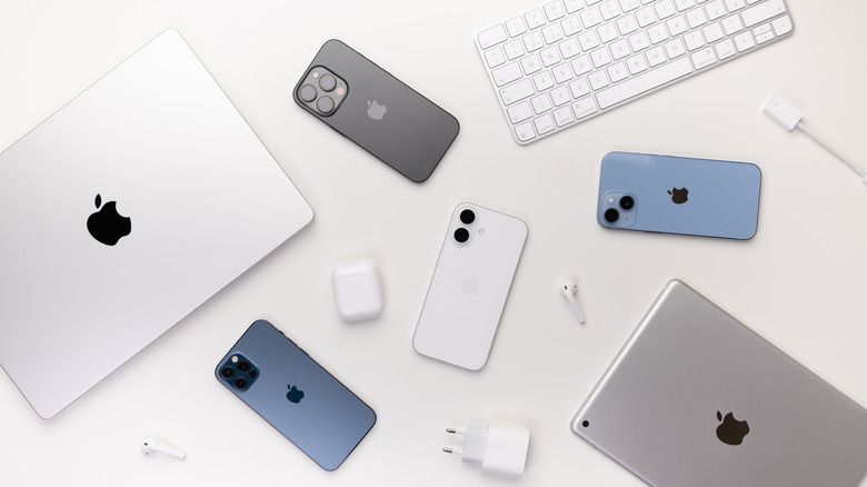 Various Apple products on a table, including iPhones, iPad, MacBook, AirPods, and accessories.