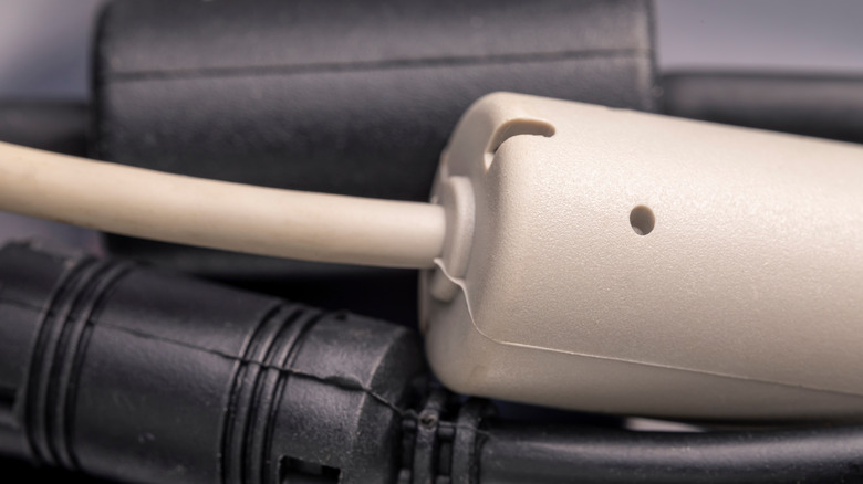 A white cable with a ferrite bead on top of two black cables with ferrite beads