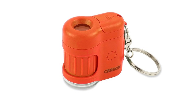 The orange Carson MicroMini microscope has a plastic body with an adjustable scope, a hook that is attached to a keychain, and the Carson label on its body
