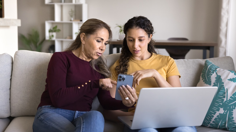 Mother and daughter having discussion with electronics in view.