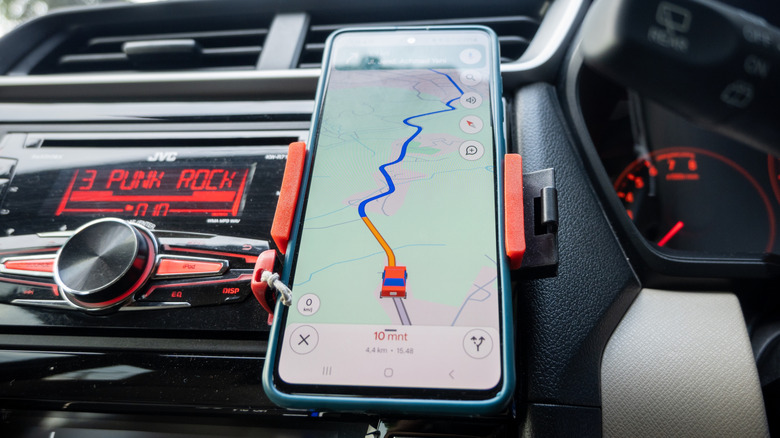 a car navigation app on a phone showing a route mounted to a dashboard