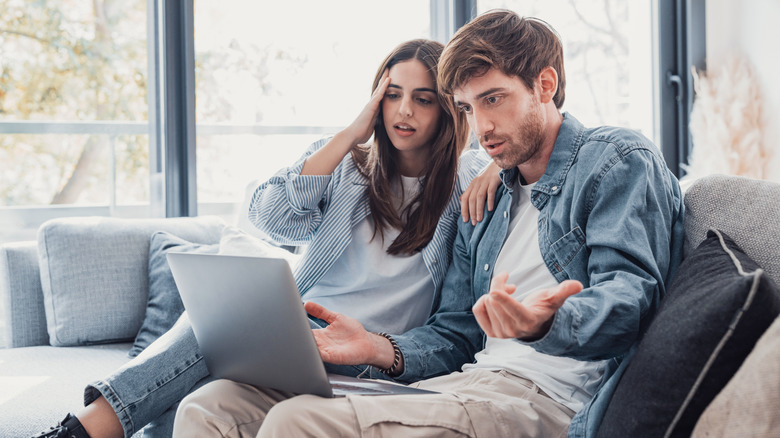 A couple looking in disbelief at their laptop