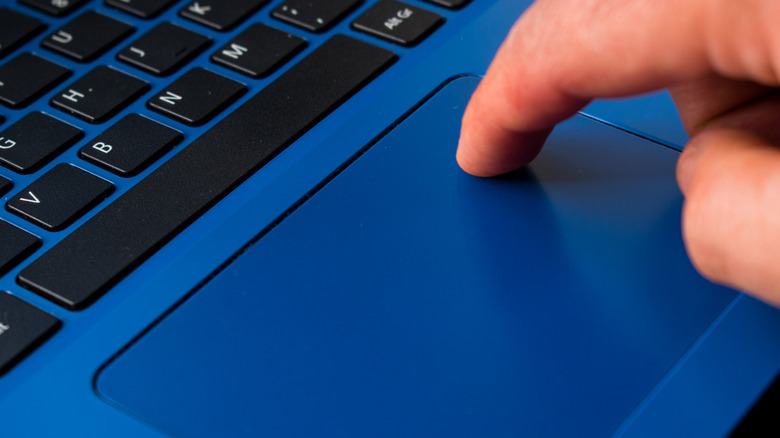 Finger resting on a laptop touchpad.