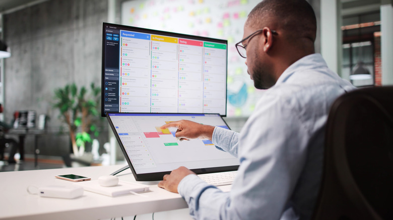 A man using a touchscreen monitor along with a traditional monitor