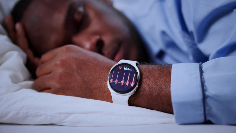 man sleeping with smartwatch tracking heartrate and other vitals
