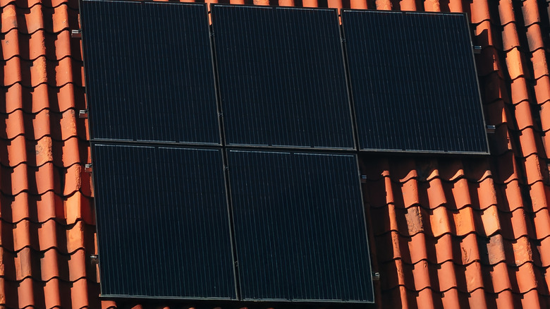 Black solar panels installed on a red terracotta tiled roof