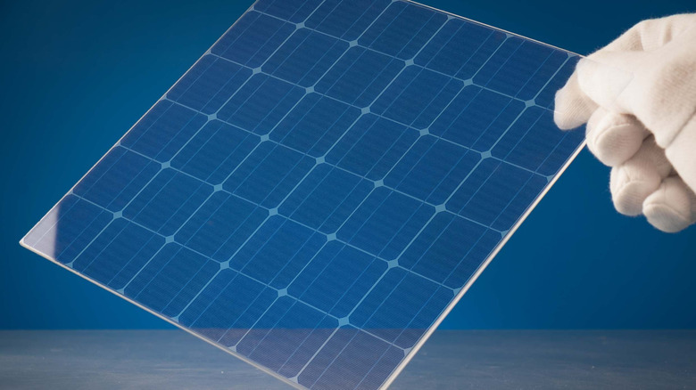 An illustration showing a transparent solar panel held by a person's fingers