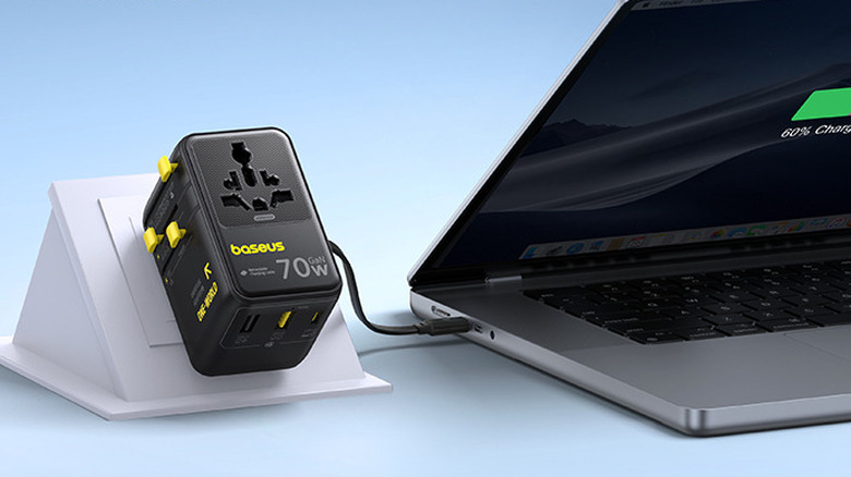 The Baseus 70W Universal Travel Adapter plugged in, with its USB-C cable charging a laptop.
