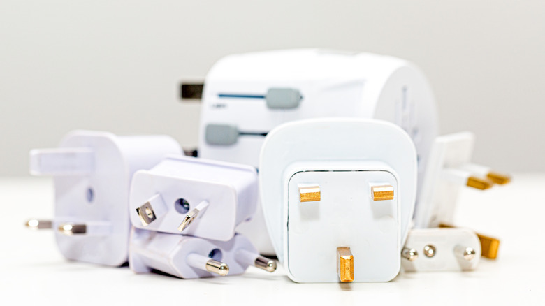 Different kinds of travel adapters on a white surface.