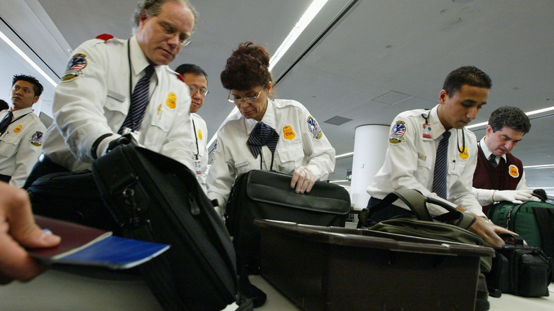 TSA agents closely examining luggage and bags at security checkpoint