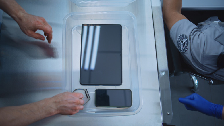 Person putting electronic in bin in TSA line
