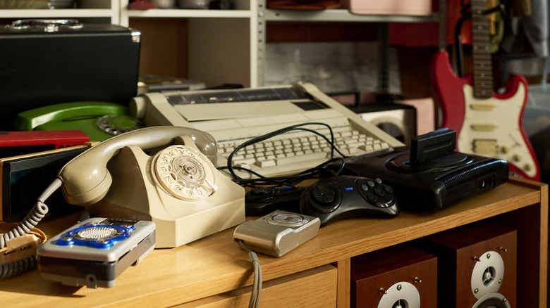 A variety of electronics including video games and speakers sitting on a shelf at a thrift store