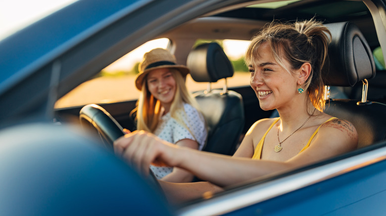 two young women driving in a car happy