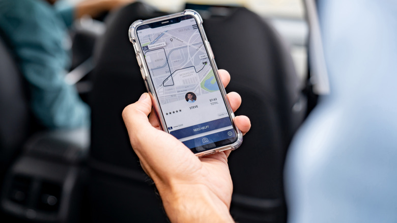 A person examining a rideshare app while sitting in the backseat of a vehicle