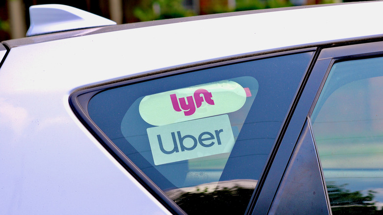 A vehicle displaying logos for Uber and Lyft in the window