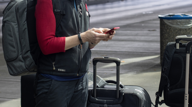 A traveller with their luggage waiting for an Uber or Lyft ride