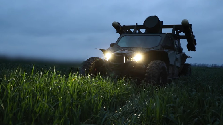 The Tempest, a buggy equipped with missile launchers, drives through a field at night.