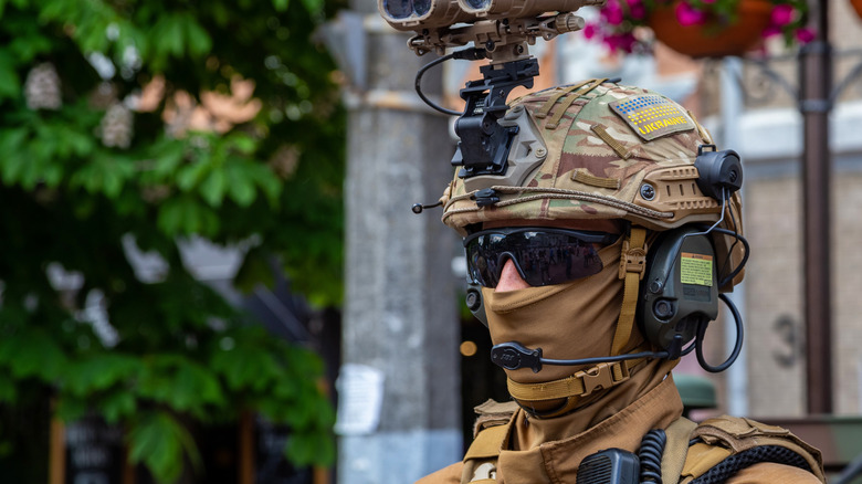 a Ukrainian soldier wearing sunglasses and a mask in an urban area