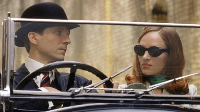 John Steed (Ralph Fiennes) and Emma Peel (Uma Thurman) looking at each other sat in a car