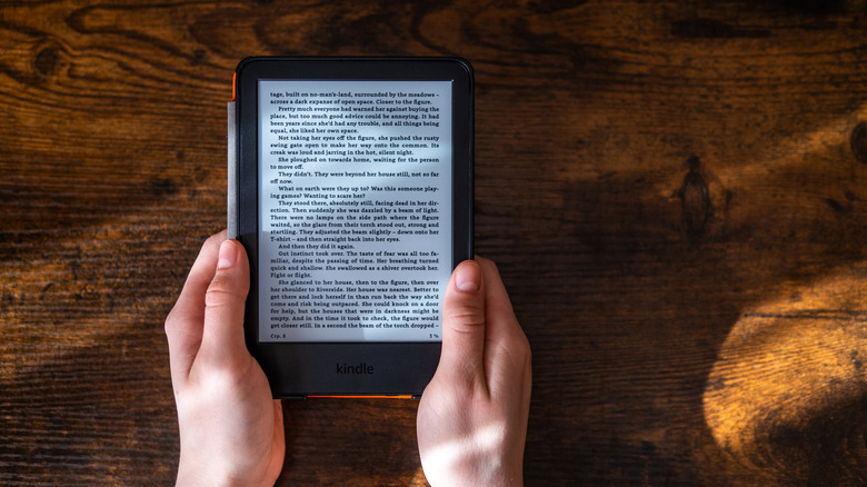 Two hands holding Kindle with case on showing text on screen